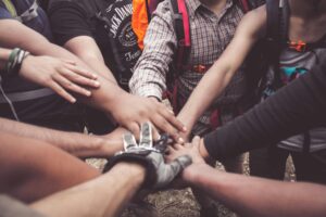 Several individuals join hands together, representing unity and collaborative effort in a group setting.